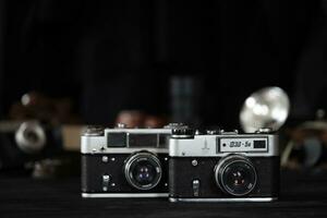 KHARKOV, UKRAINE - APRIL 27, 2021 Fed 4 and 5b Film photo camera and another old retro photo equipment on black wooden table in photographer darkroom. Photographic gear from soviet union