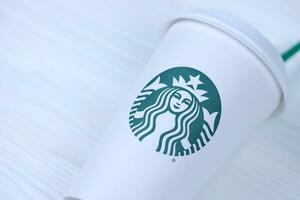 KHARKOV, UKRAINE - MARCH 15, 2021 Starbucks cup with green logo. Starbucks Corporation is multinational chain of coffeehouses headquartered in Seattle, Washington photo