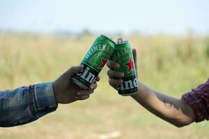 KHARKOV, UKRAINE - JULY 31, 2021 Green tin cans of Heineken pale lager beer in men hands photo