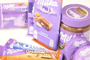 kharkov, ucrania - 2 de julio de 2021 productos de chocolate milka con diseño de envoltura de color lila clásico en mesa blanca foto