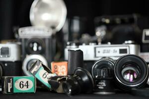 KHARKOV, UKRAINE - APRIL 27, 2021 Film photo cameras and another old retro photo equipment on black wooden table in photographer darkroom. Photographic gear from soviet union