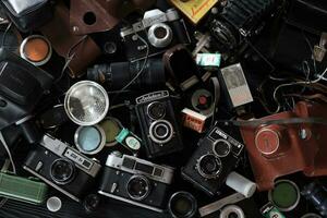 KHARKOV, UKRAINE - APRIL 27, 2021 Film photo cameras and another old retro photo equipment on black wooden table in photographer darkroom. Photographic gear from soviet union