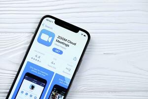 KHARKOV, UKRAINE - MARCH 5, 2021 Zoom messenger icon and application from App store on iPhone 12 pro display screen on white table photo
