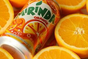 KYIV, UKRAINE - JULY 7, 2023 Mirinda orange drink with many oranges on colorful background photo