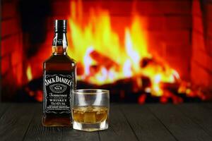 KYIV, UKRAINE - MAY 4, 2022 Jack Daniels original alcohol bottle on wooden table with red fireplace photo