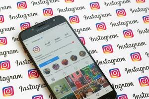 Main official instagram account on smartphone screen on paper instagram banner. photo