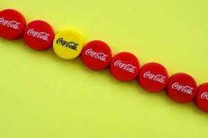 Many red caps with coca cola logo on yellow background photo