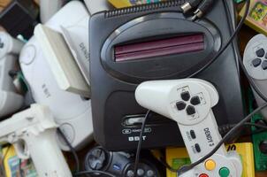 Pile of old 8-bit video game consoles and many gaming accessories like a joysticks and cartridges photo