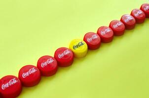 Many red caps with coca cola logo on yellow background photo
