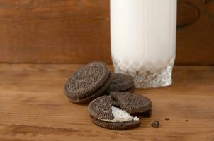 Many OREO sandwich cream biscuits and milk glass on wooden background photo