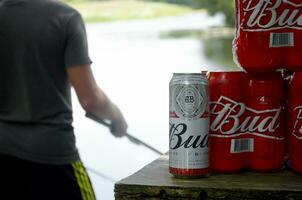 Budweiser Bud beer cans pack on old table and fisherman at river on background photo