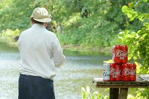Budweiser Bud beer cans pack on old table and fisherman at river on background photo