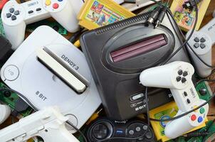 Pile of old 8-bit video game consoles and many gaming accessories like a joysticks and cartridges photo