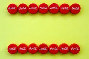 Many red caps with coca cola logo on yellow background photo
