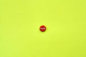 Single red bottle lid with Coca Cola logo on yellow background photo