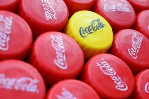 Many red lids and one yellow plastic cap with coca cola logo close up photo