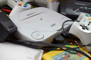 Pile of old 8-bit video game consoles and many gaming accessories like a joysticks and cartridges photo