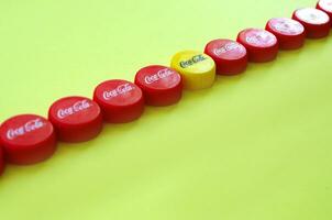 Many red caps with coca cola logo on yellow background photo