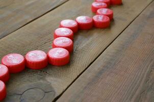 Many red caps with coca cola logo on wooden background photo