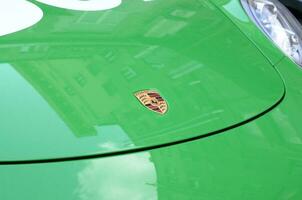 Porsche 911 Carrera 4S in green color with frontal main logo close up photo