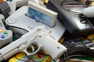 Pile of old 8-bit video game consoles and many gaming accessories like a joysticks and cartridges photo