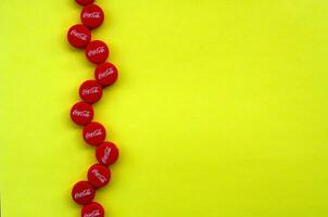 Many red caps with coca cola logo on yellow background photo