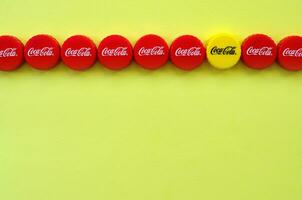 Many red caps with coca cola logo on yellow background photo