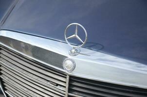 Mersedes Benz logo in old car front part close up outdoors photo