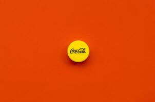 Single yellow bottle lid with Coca Cola logo on red background photo