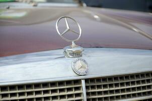 Mersedes Benz logo in old car front part close up outdoors photo