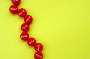 Many red caps with coca cola logo on yellow background photo