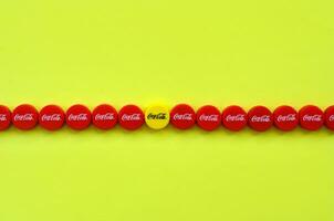 Many red caps with coca cola logo on yellow background photo
