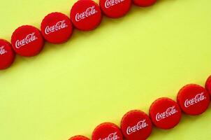 Many red caps with coca cola logo on yellow background photo