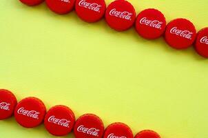 Many red caps with coca cola logo on yellow background photo