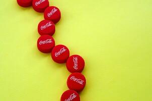 Many red caps with coca cola logo on yellow background photo