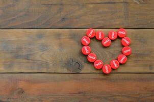 Heart of many red caps with coca cola logo on wooden background photo
