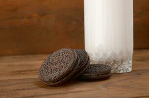 muchos oreo emparedado crema galletas y Leche vaso en de madera antecedentes foto