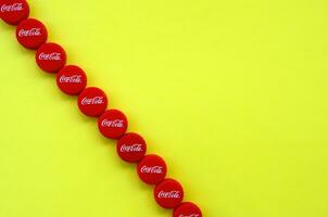 Many red caps with coca cola logo on yellow background photo