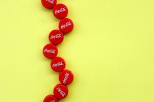 Many red caps with coca cola logo on yellow background photo