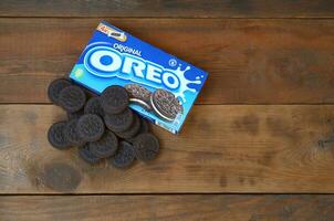 Many OREO sandwich cream biscuits with pack on wooden background photo