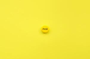 Single yellow bottle lid with Coca Cola logo on yellow background photo