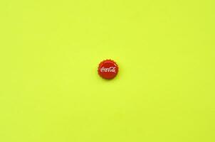 Single red bottle lid with Coca Cola logo on yellow background photo