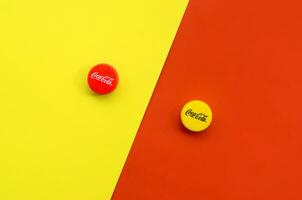Single red and yellow bottle lids with Coca Cola logo on yellow and red sides background photo