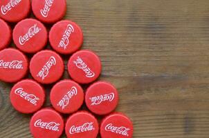 Many red caps with coca cola logo on wooden background photo