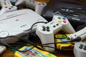 Pile of old 8-bit video game consoles and many gaming accessories like a joysticks and cartridges photo