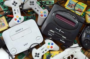 Pile of old 8-bit video game consoles and many gaming accessories like a joysticks and cartridges photo