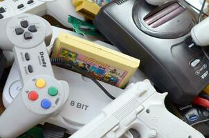 Pile of old 8-bit video game consoles and many gaming accessories like a joysticks and cartridges photo