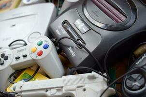 Pile of old 8-bit video game consoles and many gaming accessories like a joysticks and cartridges photo