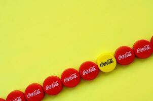 Many red caps with coca cola logo on yellow background photo