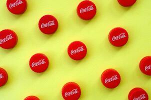 Many red caps with coca cola logo on yellow background photo